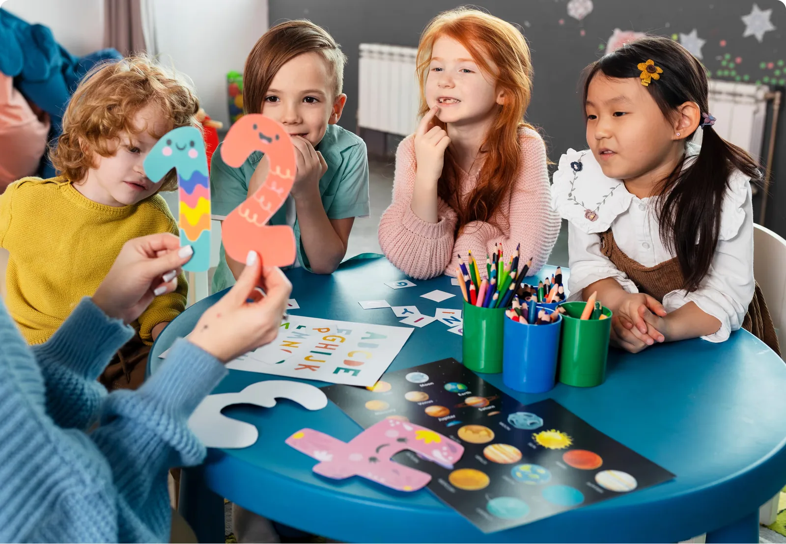 A group of children making things at a craft table with an educator