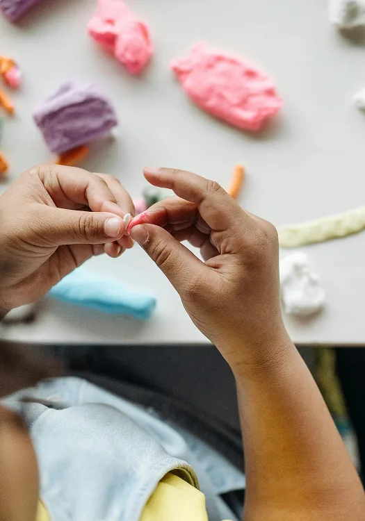 Hands shaping small pieces of coloured modelling clay